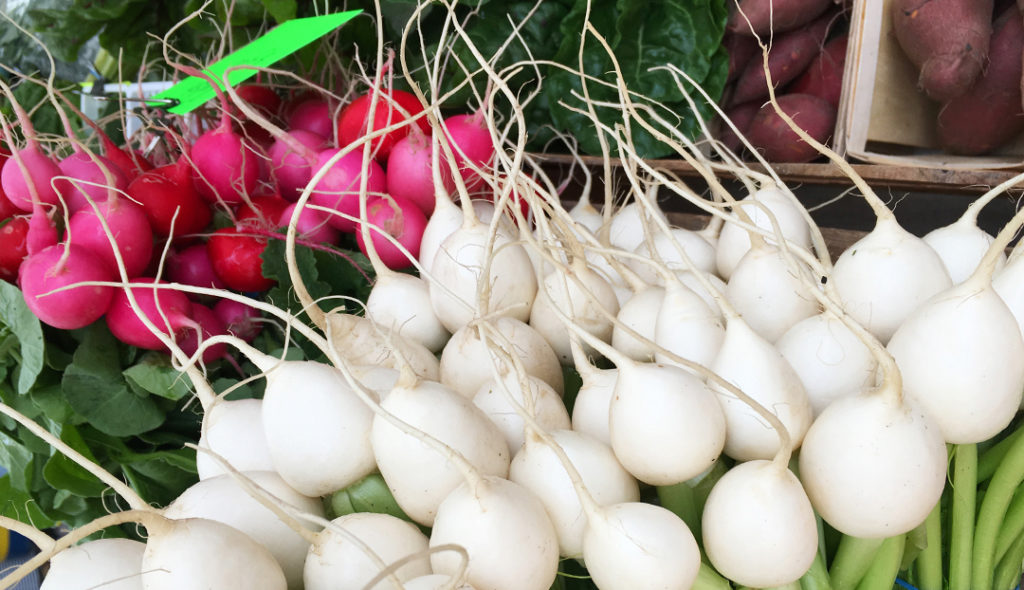 Radishes onions and sweet potatoes at the farmers market