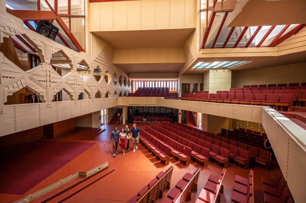 4 people inside Annie Pfeiffer Chapel, designed by Frank Lloyd Wright, on the campus of Florida Southern College in Lakeland, FL