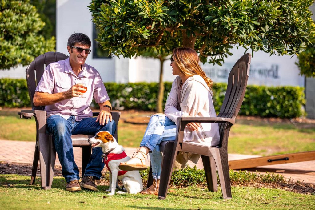 couple sitting outside on deck chairs with dog at Grove Roots Brewing Company in Winter Haven, FL