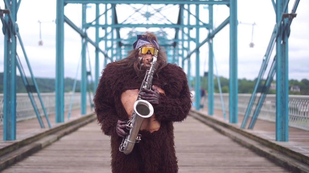 saxsquatch playing saxophone on a bridge